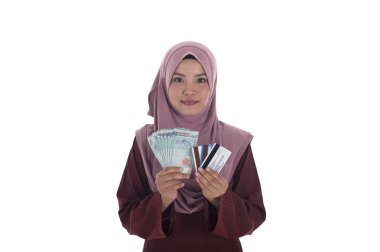 Malezya ringgiti bir sürü tutan gülümseyen bir Müslüman kadın ve 