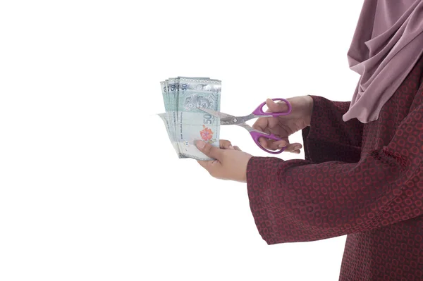 A muslim woman cutting a bunch of Malaysian Ringgit using a scis — Stock Photo, Image