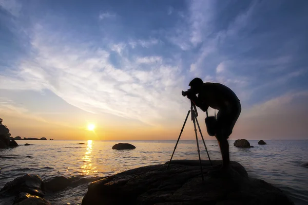 Silhouette a photographer taking pictures of sunrise on a rock, — Stock Photo, Image