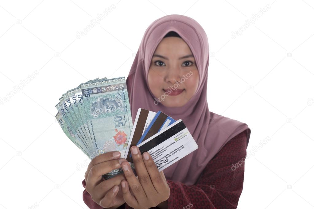 A smiling muslim woman holding a bunch of Malaysian Ringgit and 