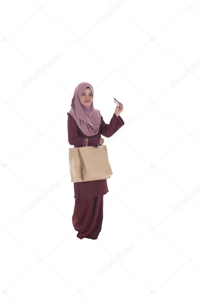 A happy muslim woman holding a bunch of shopping paper bags and 