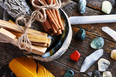 Beyaz adaçayı demeti, tarçın çubukları ve deniz kulağı kabuğundaki palo santo ile yakın plan bir resim.. 