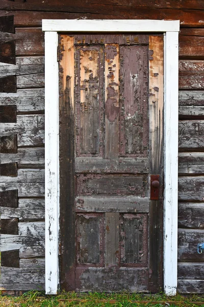An image of an old run down door with dark brown peeling paint.