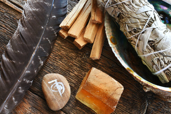 A top view image of white sage smudge stick with healing crystals, sacred feather and reiki symbol.