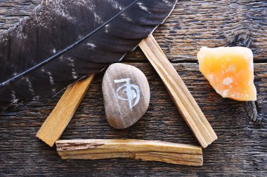 A top view image of a reiki healing symbol and palo santo smudge sticks on a dark wooden table top.  clipart