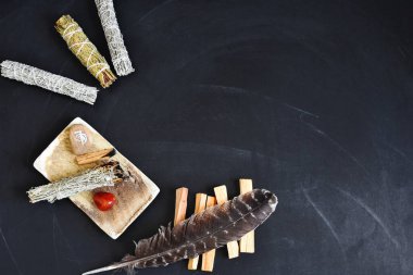 A top view image of a healing smudge kit with white sage and crystals on a black background. 