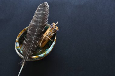 İyileştirici bir leke çubuğu ve siyah arka planda deniz kulağı kabuğundaki kutsal tüy görüntüsü.. 