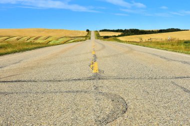 Güneşli bir günde terk edilmiş eski kırsal bir asfalt otoyolunun görüntüsü..  