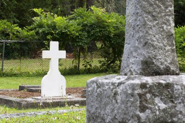 Vancouver Adası 'ndaki eski ve bakımlı bir mezarlıkta büyük beyaz bir granit haçın görüntüsü..