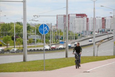 MINSK, BELARUS - 1 EKİM, 2020: Bir adam şehir merkezinde bisiklet yolunda bisiklet sürüyor