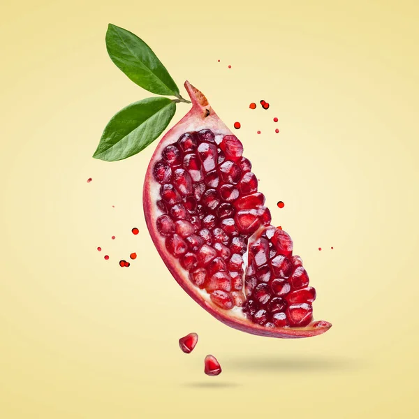 Tohumları ve yaprakları havada uçuşan olgun bir nar. Nar meyveli arkaplan.