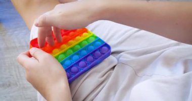 Çocuk popüler masa oyunu oynuyor. Stres önleyici oyuncağı aç. Çok renkli popüler silikon anti-stres oyuncağı patlat..