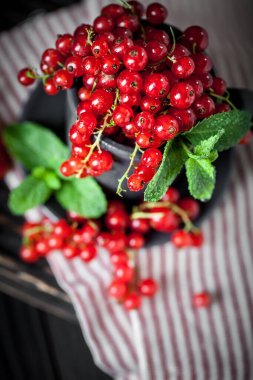 Bir kasede olgun kırmızı frenk üzümü. Koyu kırsal ahşap masada taze kırmızı frenk üzümü. Kopya alanı olan bir arkaplan. Seçici odak.