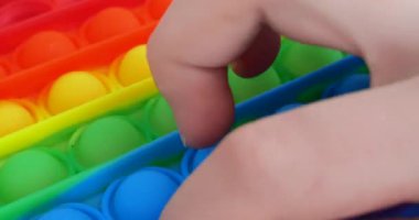 Çocuk popüler masa oyunu oynuyor. Stres önleyici oyuncağı aç. Çok renkli popüler silikon anti-stres oyuncağı patlat..