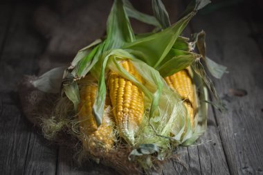 Tahta bir masada yaprakları olan taze sulu mısır. Sonbahar arkaplanı. Seçici odak.