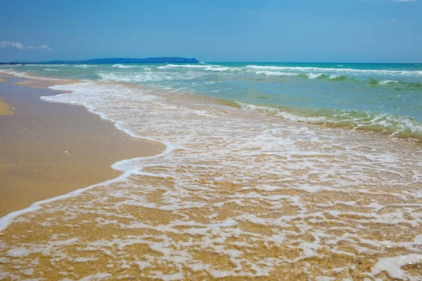 Milda havsvågor på en sandstrand, full frame natur bakgrund koncept för turism, semester och miljöskydd. Stockfoto