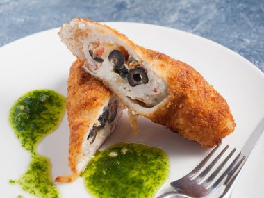 Domatesli, peynirli ve zeytinli fileto ile kızartılmış tavuk pirzolası. Kapat.