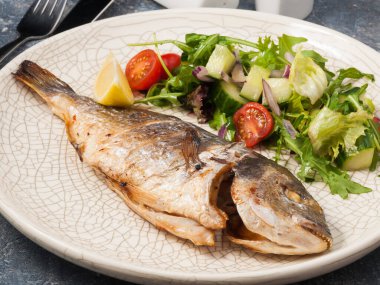 Hafif tabakta taze sebzeli kömürlü Dorado.