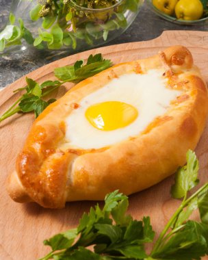 Maydanozla süslenmiş ahşap bir tahtada lezzetli Ajarian khachapuri.