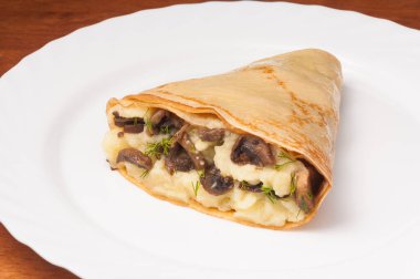 Beyaz tabakta patates ve mantarlı krep.