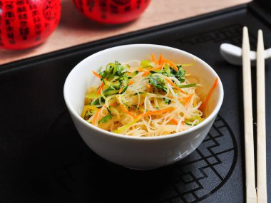 Lezzetli bir selofan, beyaz kasede sebzeler ve siyah bir arka plan.