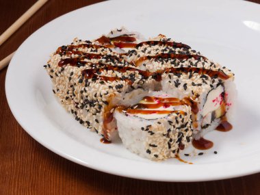 Lezzetli suşi rulosu, beyaz tabakta yılan balığı, krem peynir ve avokado.