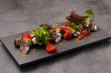 Kurutulmuş domates ve bitkilerle süslenmiş peynirli patlıcan ruloları.