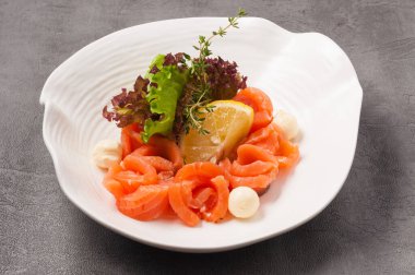 Beyaz tabakta tereyağı ve limon ile lezzetli somon balığı.