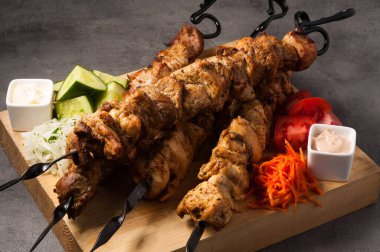 Çeşit çeşit kebap ve sebze ve soslu metal şiş.