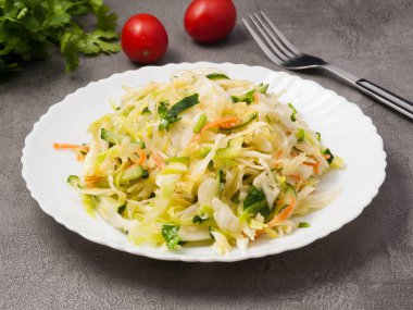 Lahanalı salata, salatalık ve beyaz tabakta havuç.