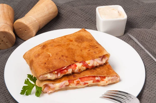 Pfannkuchen mit Schinken, Käse und Tomaten auf einem weißen Teller. horizontaler Rahmen Stockfoto