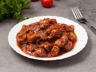 Beyaz tabakta domates ezmeli domuz kebabı.