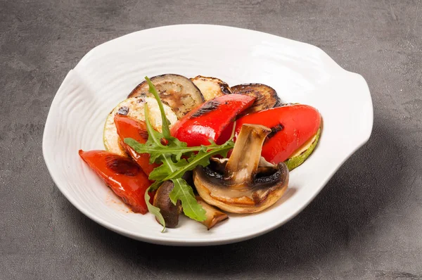 Beyaz bir tabakta lezzetli patlıcan, kabak, biber ve ızgara mantar.