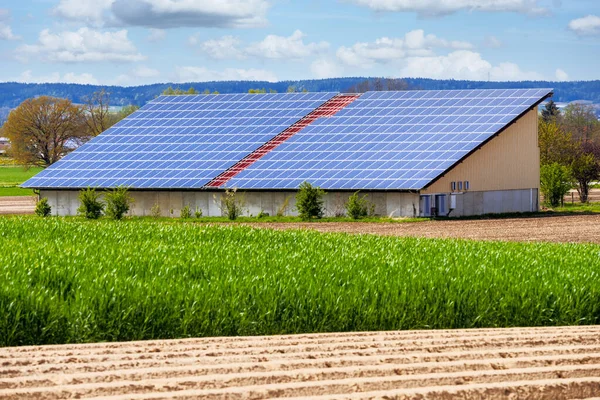 农业建筑物屋顶上有太阳能集热器的绿色能源 — 图库照片