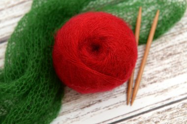 Ball of red mohair yarn and knitting needles clipart