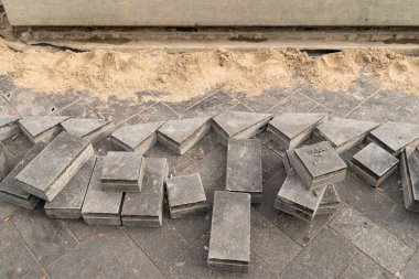 Çakıl tabakasına asfalt döşeme hazırlığı. Sıralanmış renkli kiremitler yığınlar halinde dizilmiş