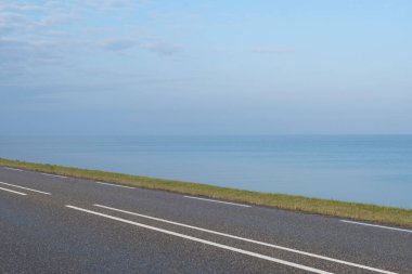 Bisiklet yolu, yol, yeşil çayır ve üzerinde göl olan mavi bir gökyüzü.