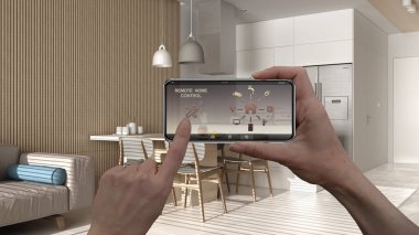Dijital akıllı telefon tabletindeki uzaktan kumanda sistemi. Uygulama simgeleri olan aygıt. Minimalist modern oturma odasının arka planında mutfak, mimari tasarım.