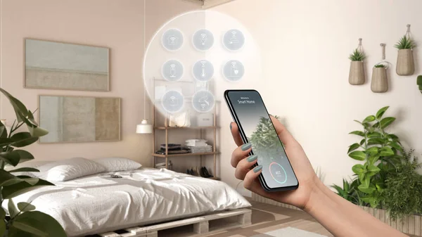 Smart home technology interface on phone app, augmented reality, internet of things, interior design of wooden bedroom with connected objects, woman hand holding remote control device