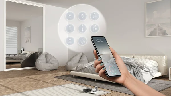 Smart home technology interface on phone app, augmented reality, internet of things, interior design of modern bedroom with connected objects, woman hand holding remote control device