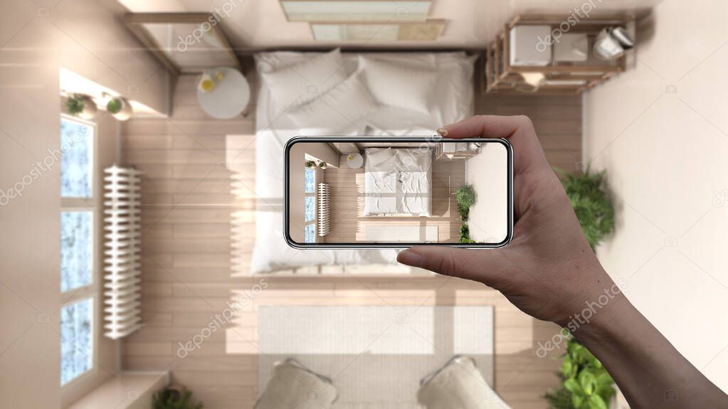 Hand holding smart phone, AR application, simulate furniture and interior design products in real home, architect designer concept, blur background, rustic country bedroom with bed