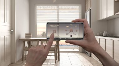 Dijital akıllı telefon tabletindeki uzaktan kumanda sistemi. Uygulama simgeleri olan aygıt. Arka planında panoramik pencere olan İskandinav mutfağının iç mimari tasarımı.