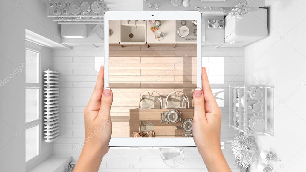 Hands holding tablet showing wooden kitchen, top view, total blank project background, augmented reality concept, application to simulate furniture and interior design products, plan