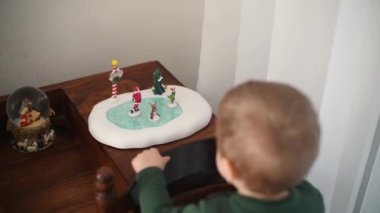 Bir çocuk Noel için seramik figürlerle oynuyor