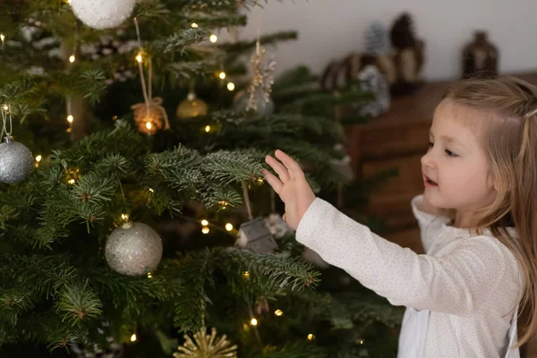 女の子はクリスマスのために木を飾る — ストック写真