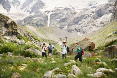 Sırt çantalı ve İskandinav sopalı kadınlar dağlara tırmanıyor.