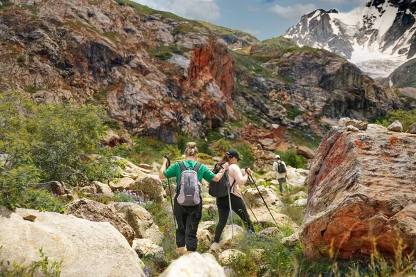 Γυναίκες με σακίδια και σκανδιναβικά μπαστούνια σκαρφαλώνουν στα βουνά. — Φωτογραφία Αρχείου
