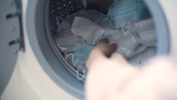 Kobieta wkłada maskę chirurgiczną do pralki — Wideo stockowe