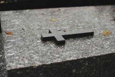 A wet cross after rain on a marble slab on a grave in a cemetery