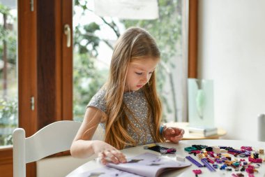 Kız talimatlara bakıyor ve plastik bir inşaat seti kuruyor. Bir Noel hediyesi.. 